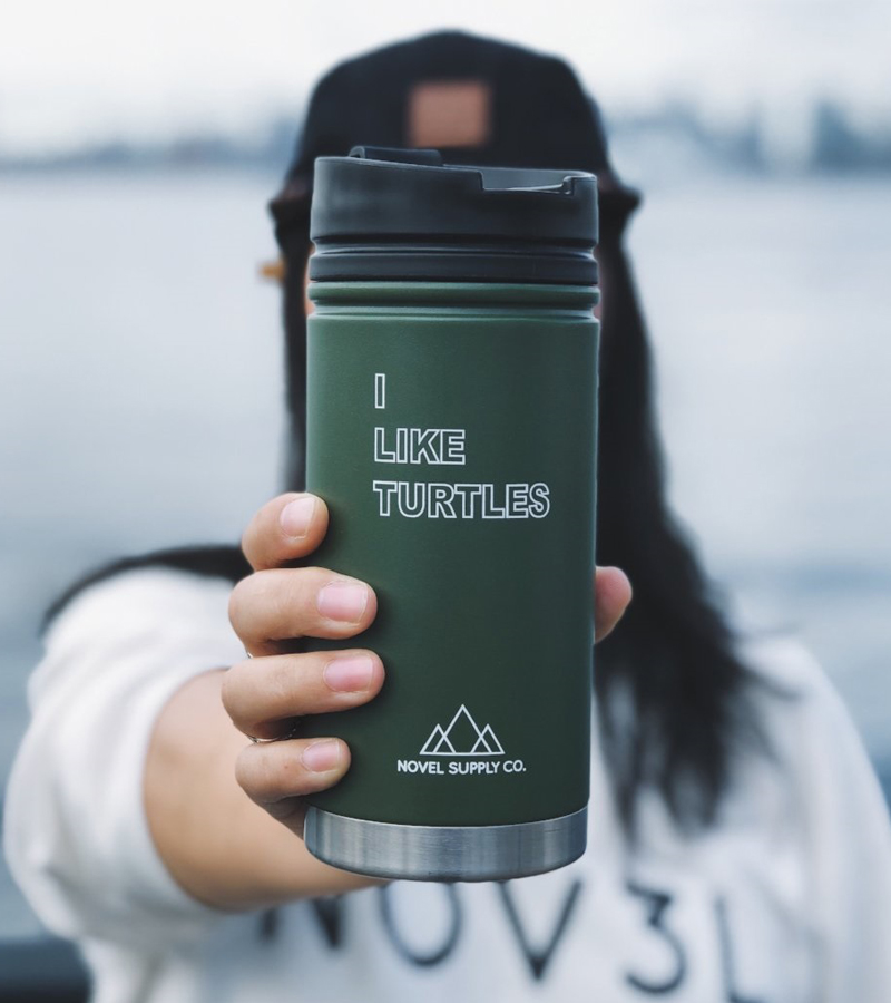 A photo of a person holding a green coffee cup that says "I like turtles"