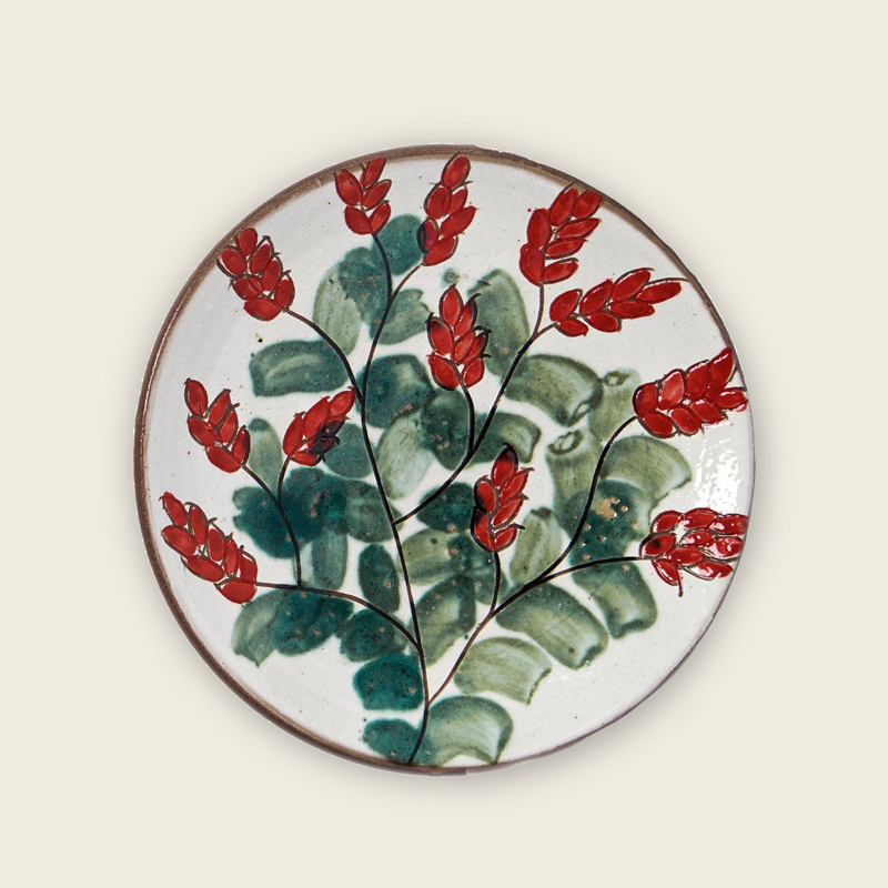 A red, white and green decorative plate with a floral design