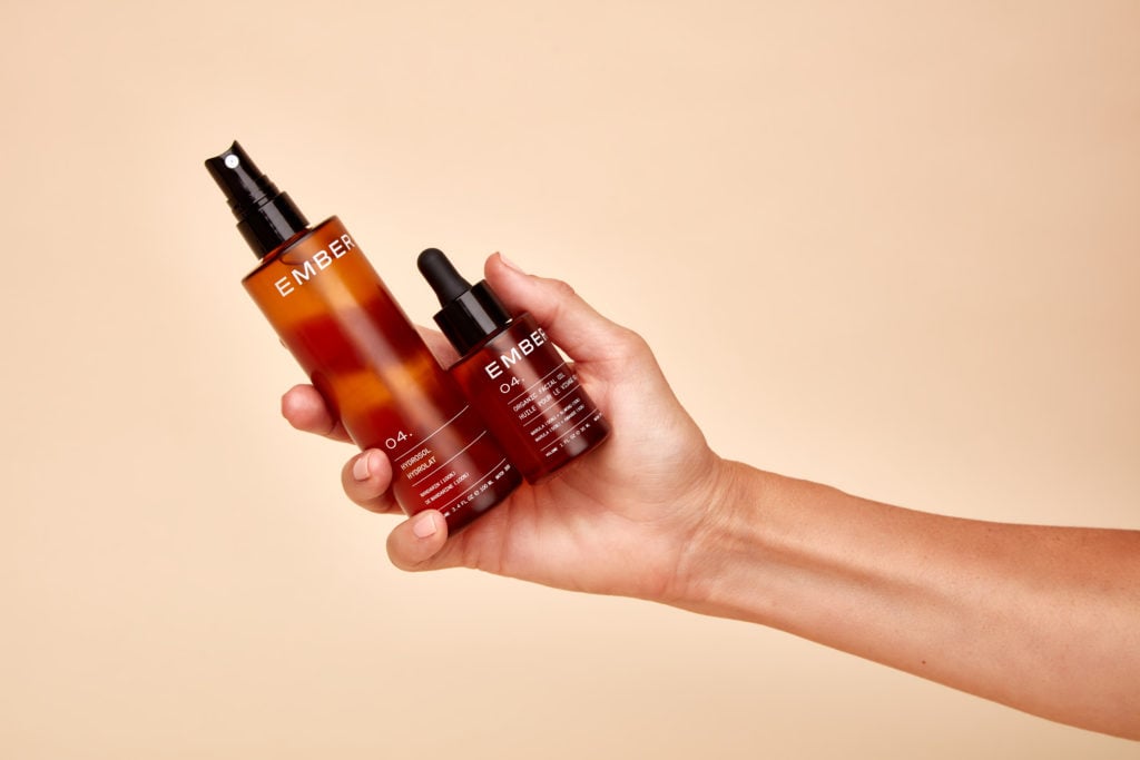 A photo of a hand holding out two Ember wellness products