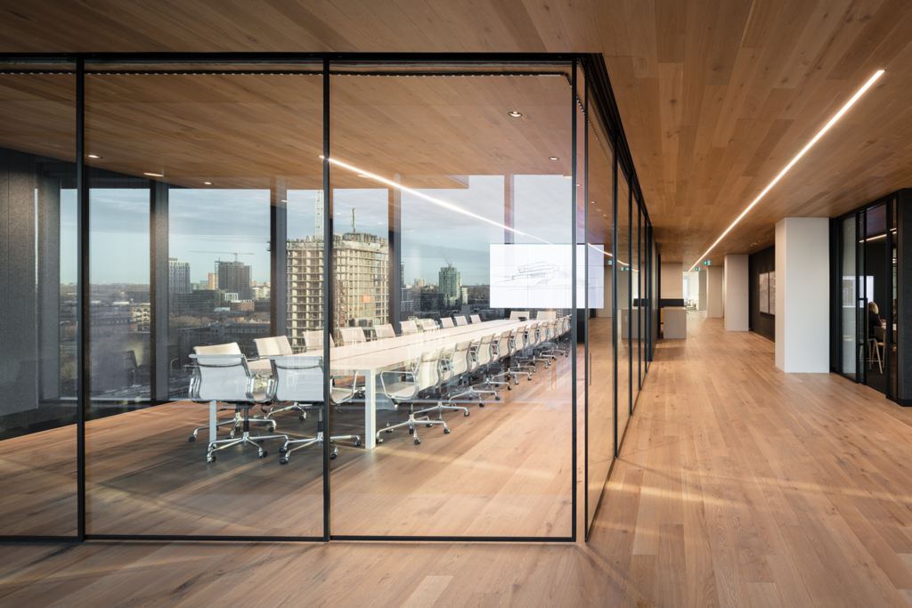 A photo of a glass boardroom with white chairs