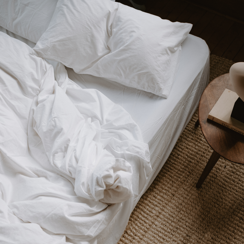 A photo of an unmade bed with white Tuck sheets on it 